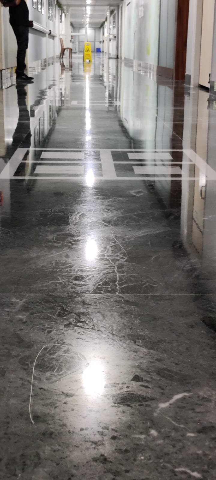 Grey marble corridor being restored, a technician working at the far end