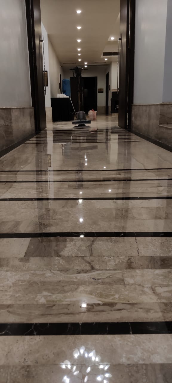 Banquet corridor in banded marble with a floor polishing machine working at the far end